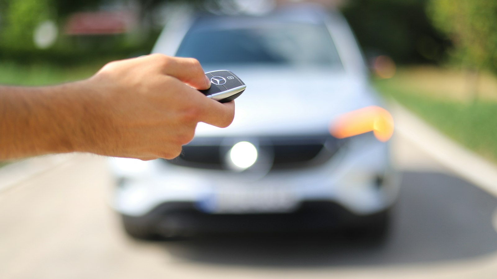 Kierowca z kluczykiem keyless w dłoni przy swoim samochodzie